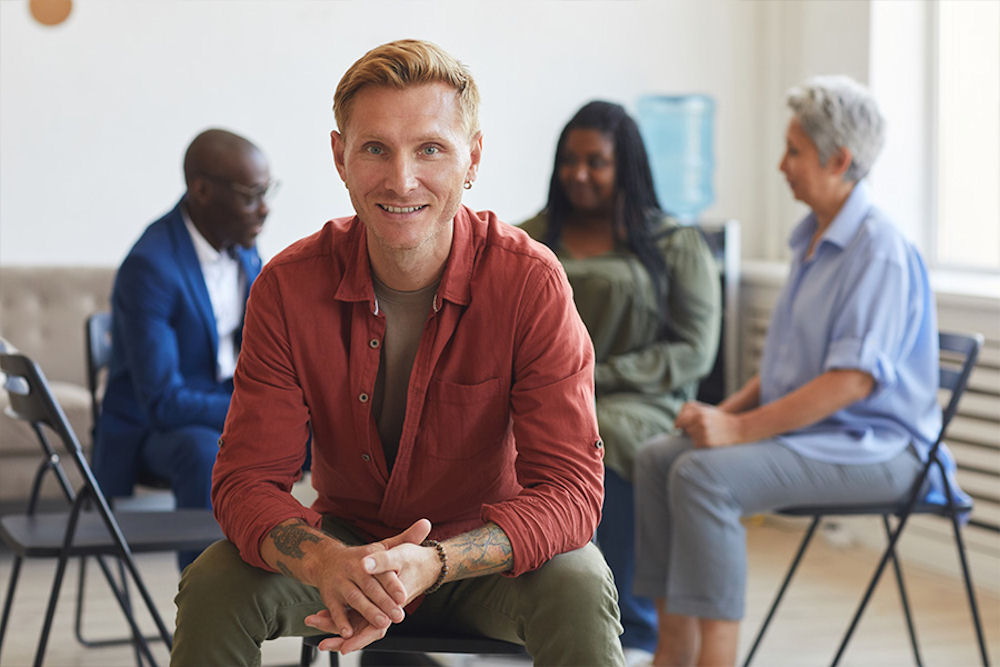 Happy young man looking out from aftercare support group in California.