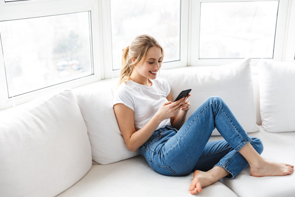 Happy young woman looking down at phone.